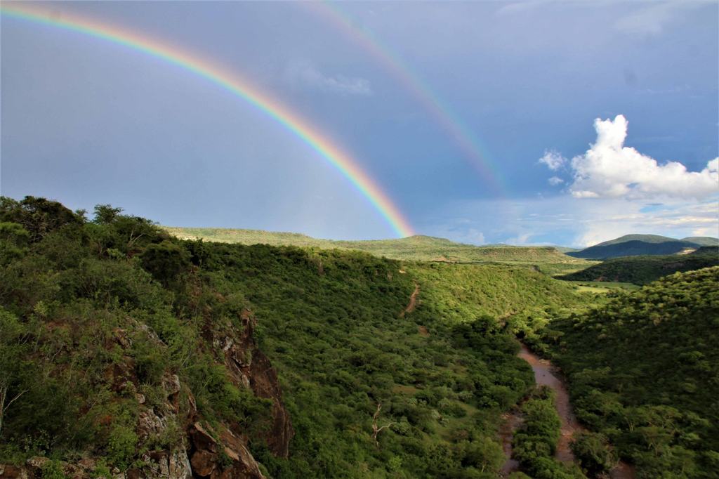 The green valley under a stormy sky with a double rainbow